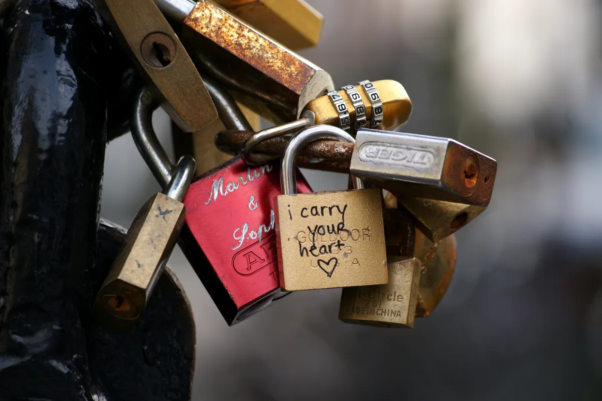 A bunch of padlocks locked together, one of which reads I Carry Your Heart, a reference to an E E Cummings poem.